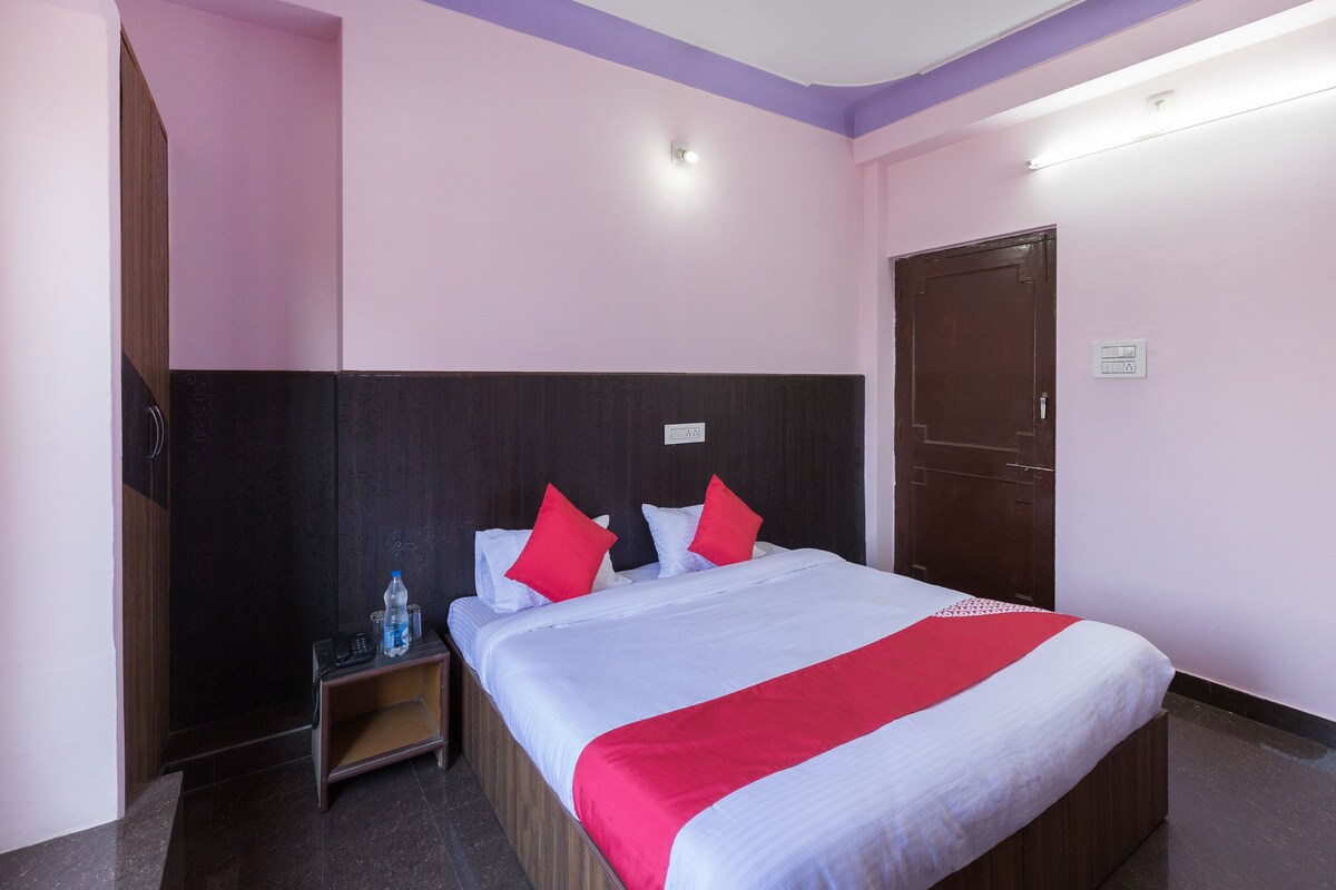 A hotel room with a bed, bedside table, and a door.