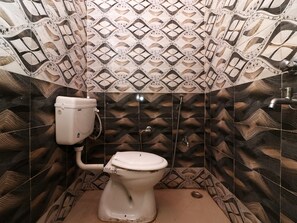 A bathroom with patterned tiles, a toilet, and a shower. - OYO 22646 Jyoti Hotel (Rewari)