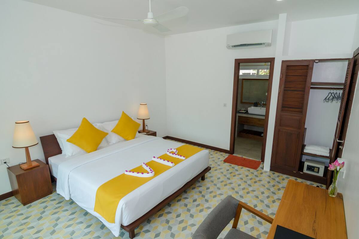 A hotel room with a bed, bedside lamps, a desk, and a wardrobe.