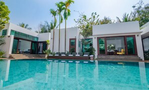 A modern house with a swimming pool, large windows, and a patio area with lounge chairs. - Draco Residence (Siem Reap)