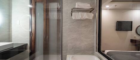 A modern bathroom with a glass shower enclosure, a built-in sink, and a large mirror.