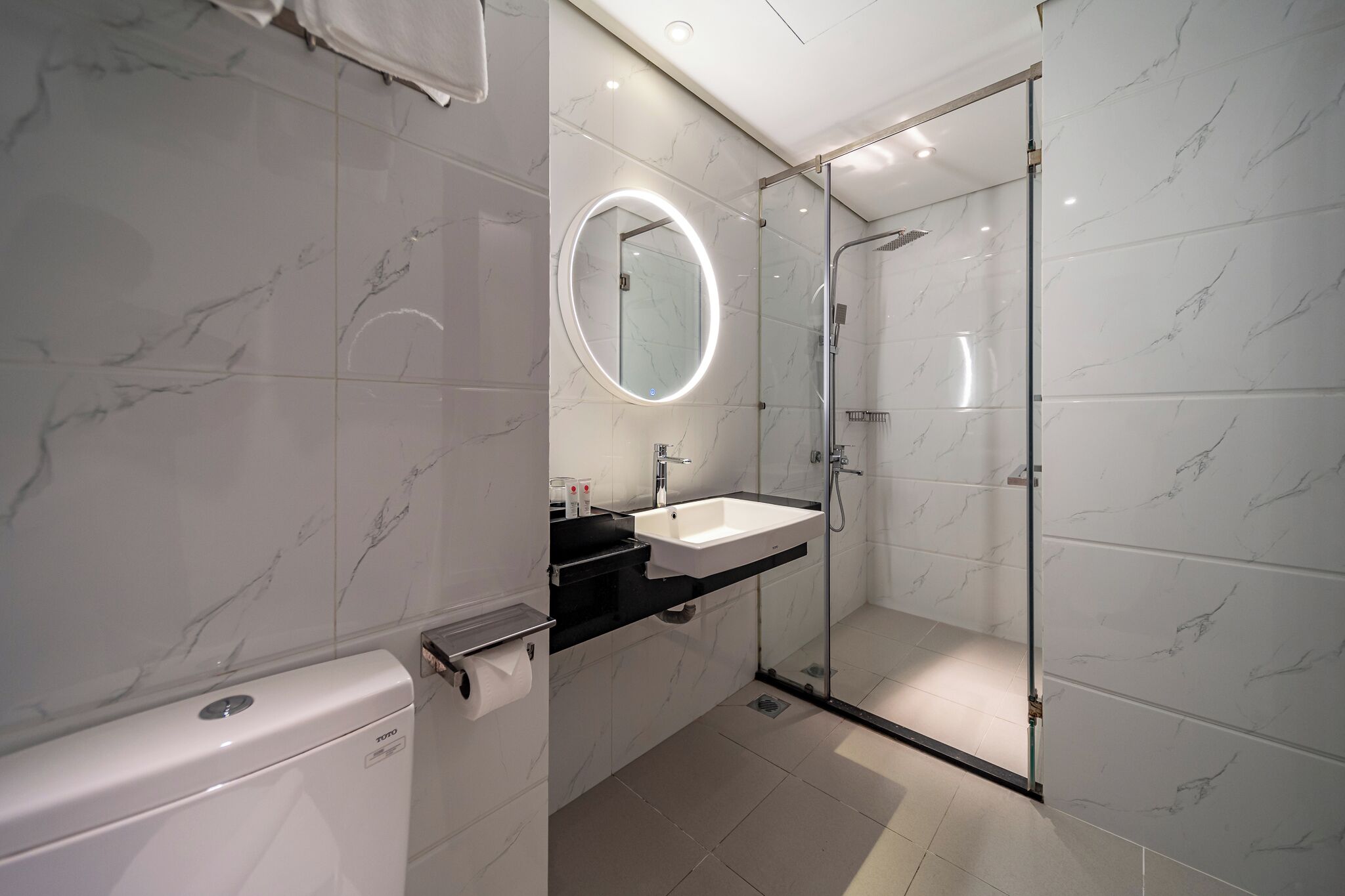 A modern bathroom with a glass-enclosed shower, a white toilet, and a vanity with a mirror.