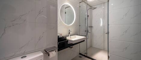 A modern bathroom with a glass-enclosed shower, a white toilet, and a vanity with a mirror.