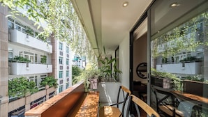 A balcony with a wooden bench and chairs, surrounded by potted plants and overlooking a cityscape. - Edoya Hotel Ben Thanh (Ho Chi Minh City)
