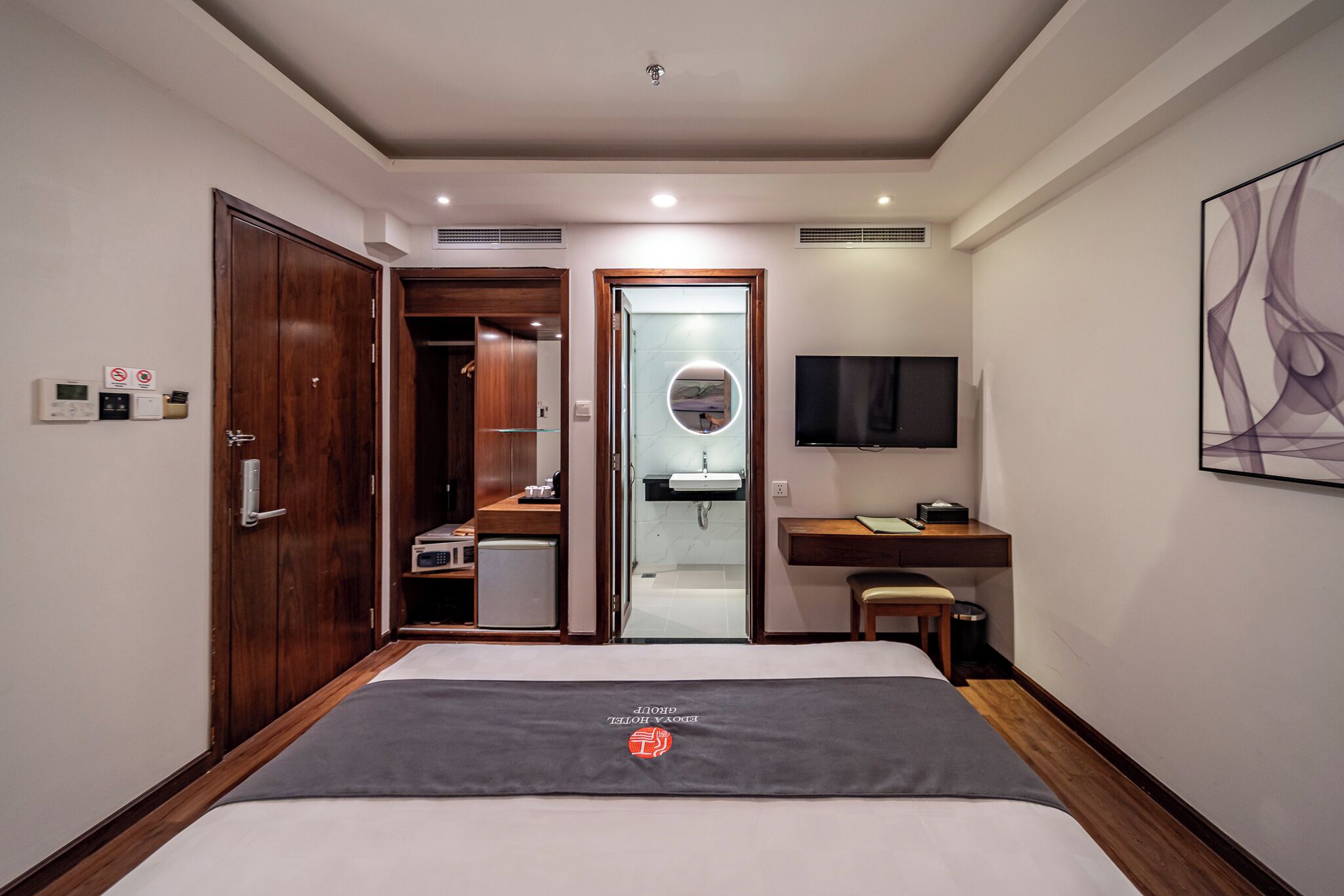 Een hotelkamer met een bed, een bureau, een televisie, een badkamer en een kledingkast.
