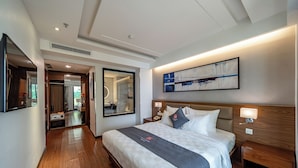 A modern hotel room with a large bed, a bedside table, a nightstand, a wall-mounted TV, and a large abstract painting. - Edoya Hotel Ben Thanh (Ho Chi Minh City)