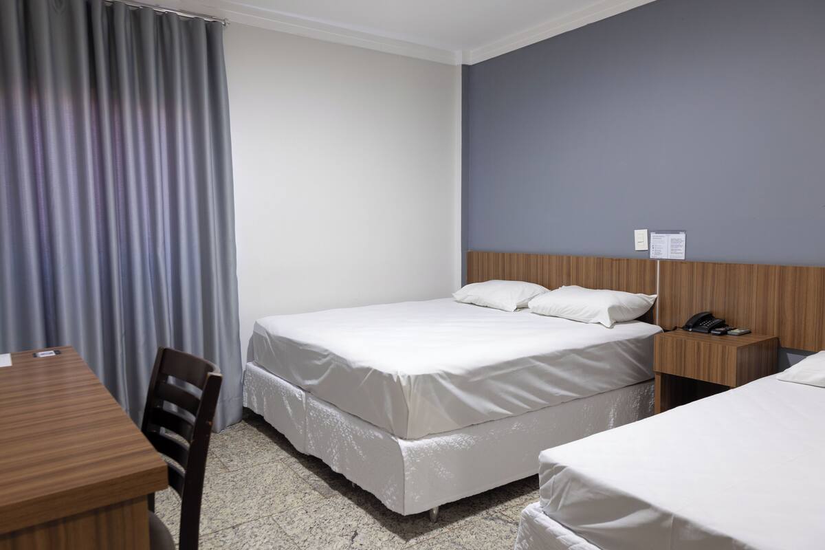 A hotel room with a bed, a desk, and a chair.