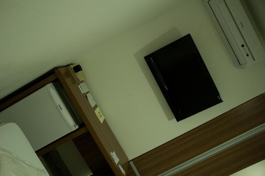 Une chambre d’hôtel équipée d’un lit, d’un bureau, d’une petite table et d’un téléviseur fixé au mur.