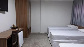 A hotel room with a wooden desk, a television, two beds, and a small kitchenette.