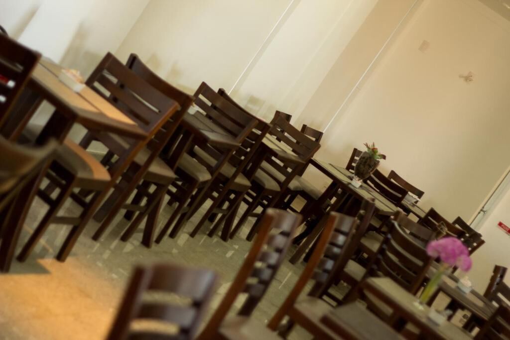 A restaurant with multiple wooden tables and chairs arranged in rows.