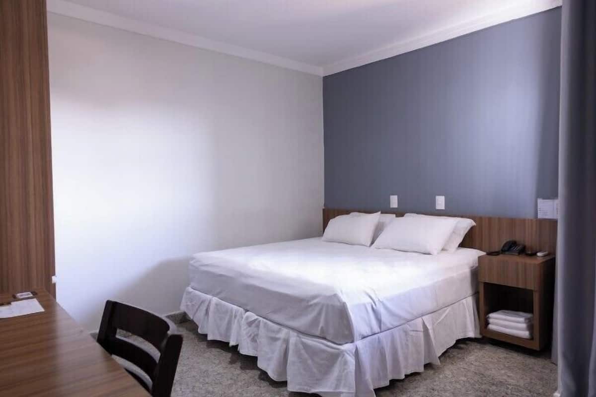 A neatly arranged bedroom with a bed, bedside table, and a chair.