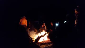 Un grupo de personas reunido alrededor de una fogata por la noche.