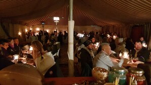 Un comedor interior con mesas, velas y gente.