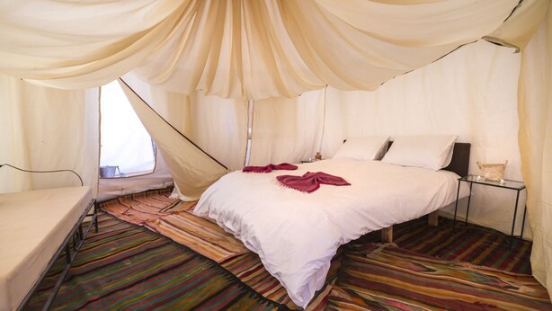 Una habitación con una cama, una mesita de noche y un ventanal.