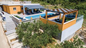 Une villa moderne dotée d’une piscine, d’un espace salon extérieur et d’une pergola.