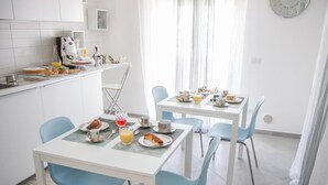 Una cocina moderna con gabinetes blancos y una zona de comedor con dos mesas y sillas azules.