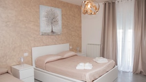 Un dormitorio con cama, mesitas de noche, un cuadro y una ventana con cortinas.