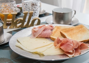 Un plato de desayuno con queso y jamón sobre tostadas, una taza y un cartel decorativo que dice 'Hello'.