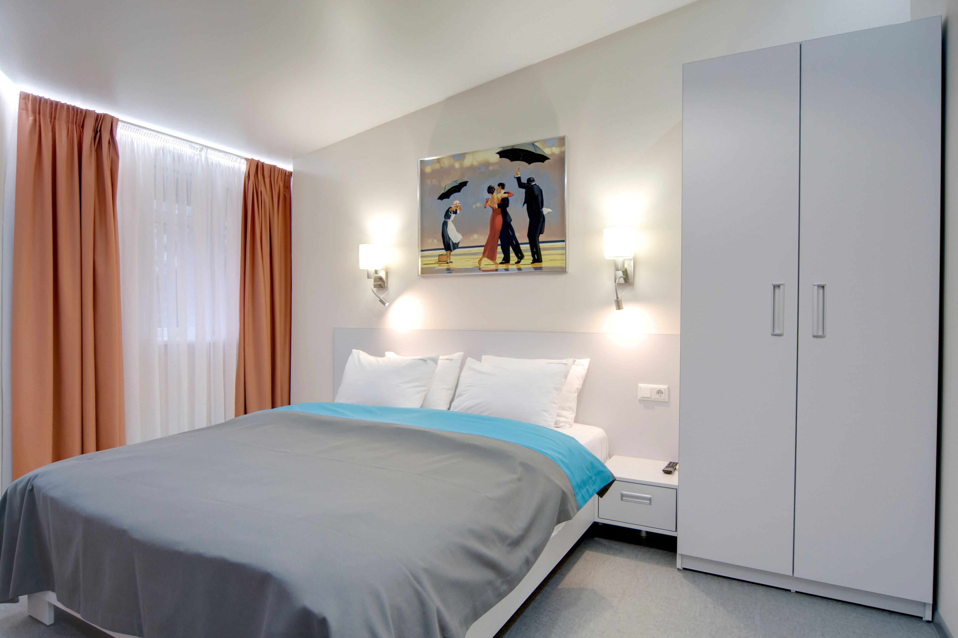 Une chambre d’hôtel avec un lit, une table de chevet, une armoire et un tableau au mur.