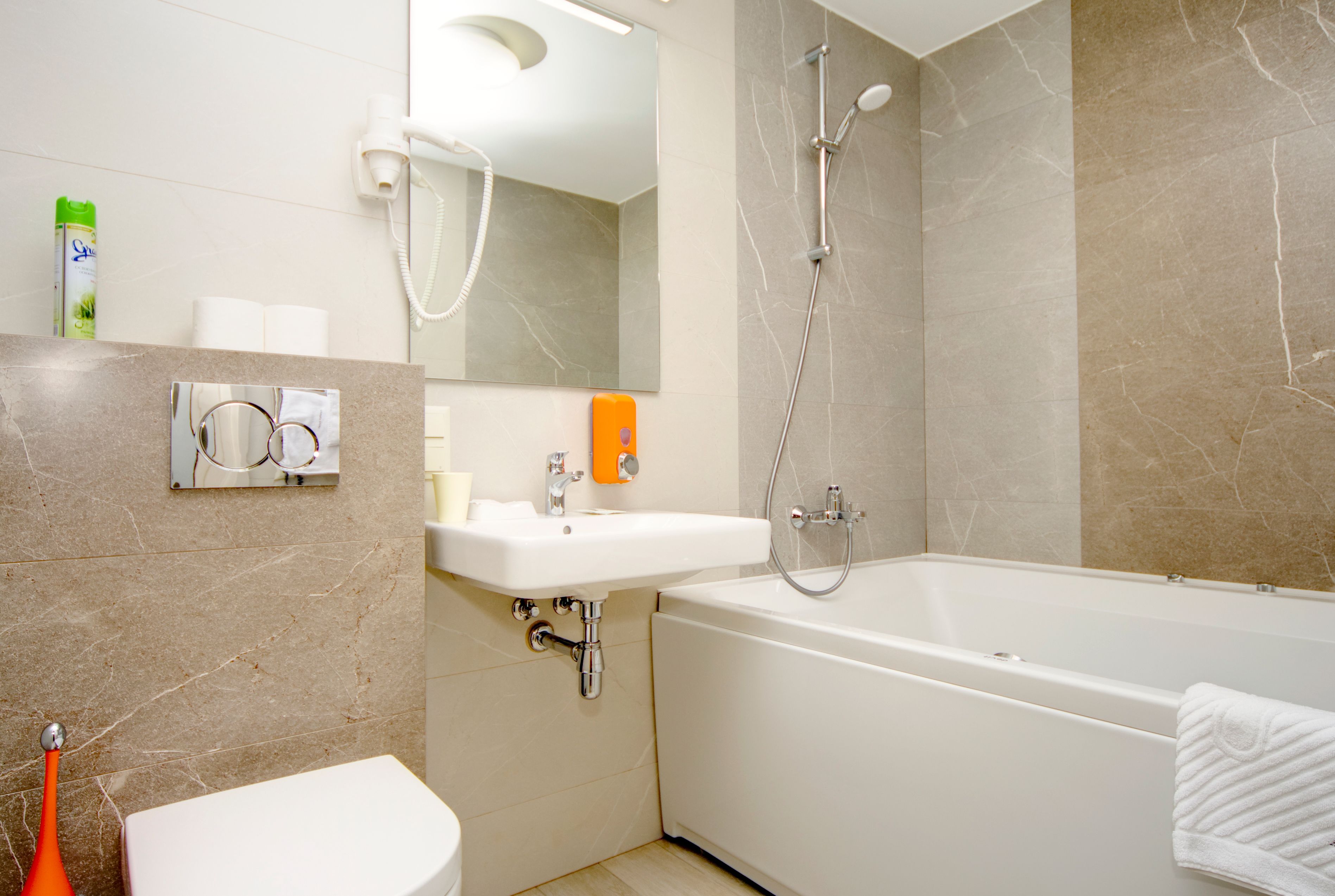 Un baño moderno con inodoro, lavamanos, espejo, ducha y bañera.