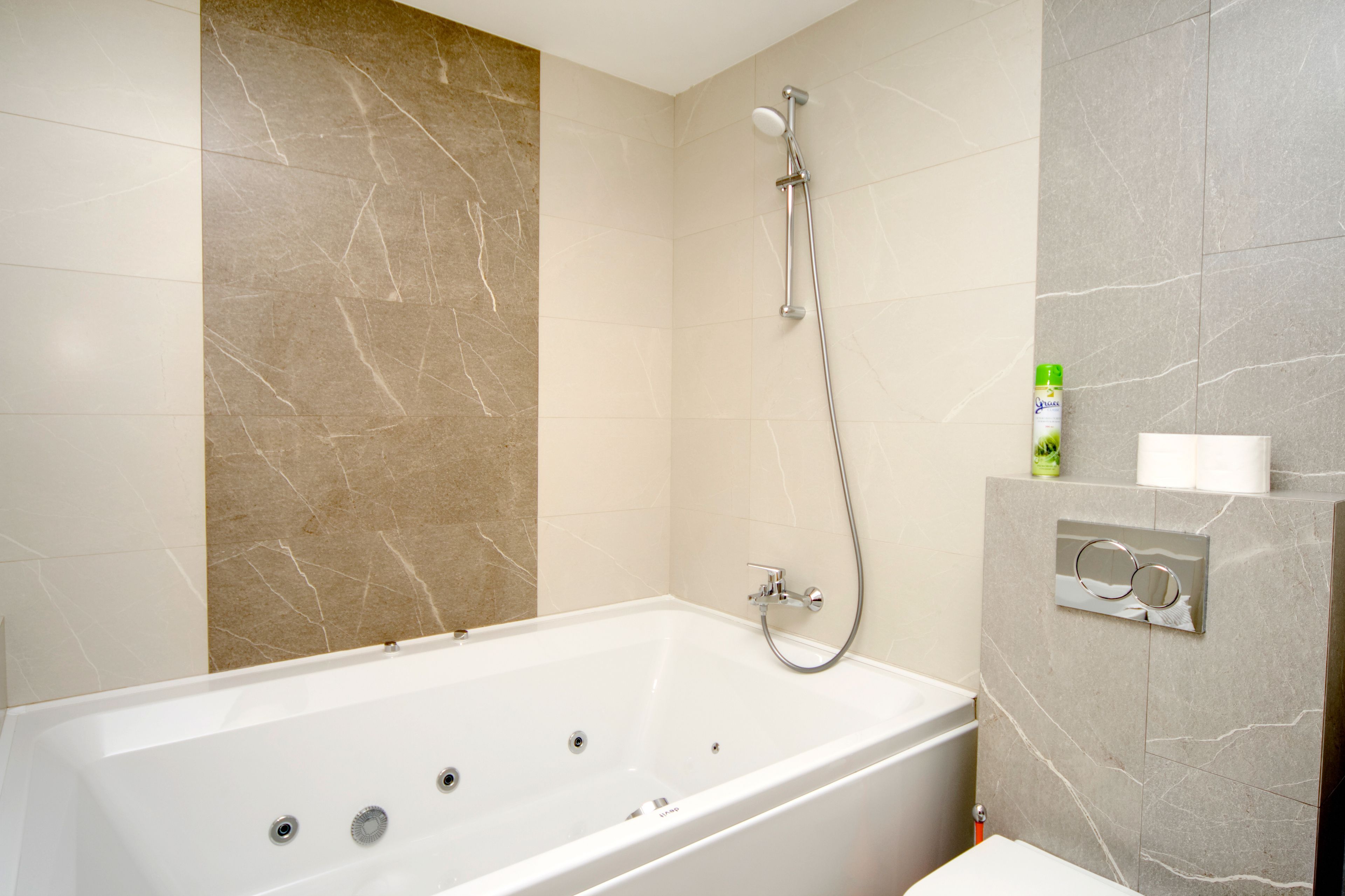 A modern bathroom with a freestanding bathtub, a handheld showerhead, and a towel rack.