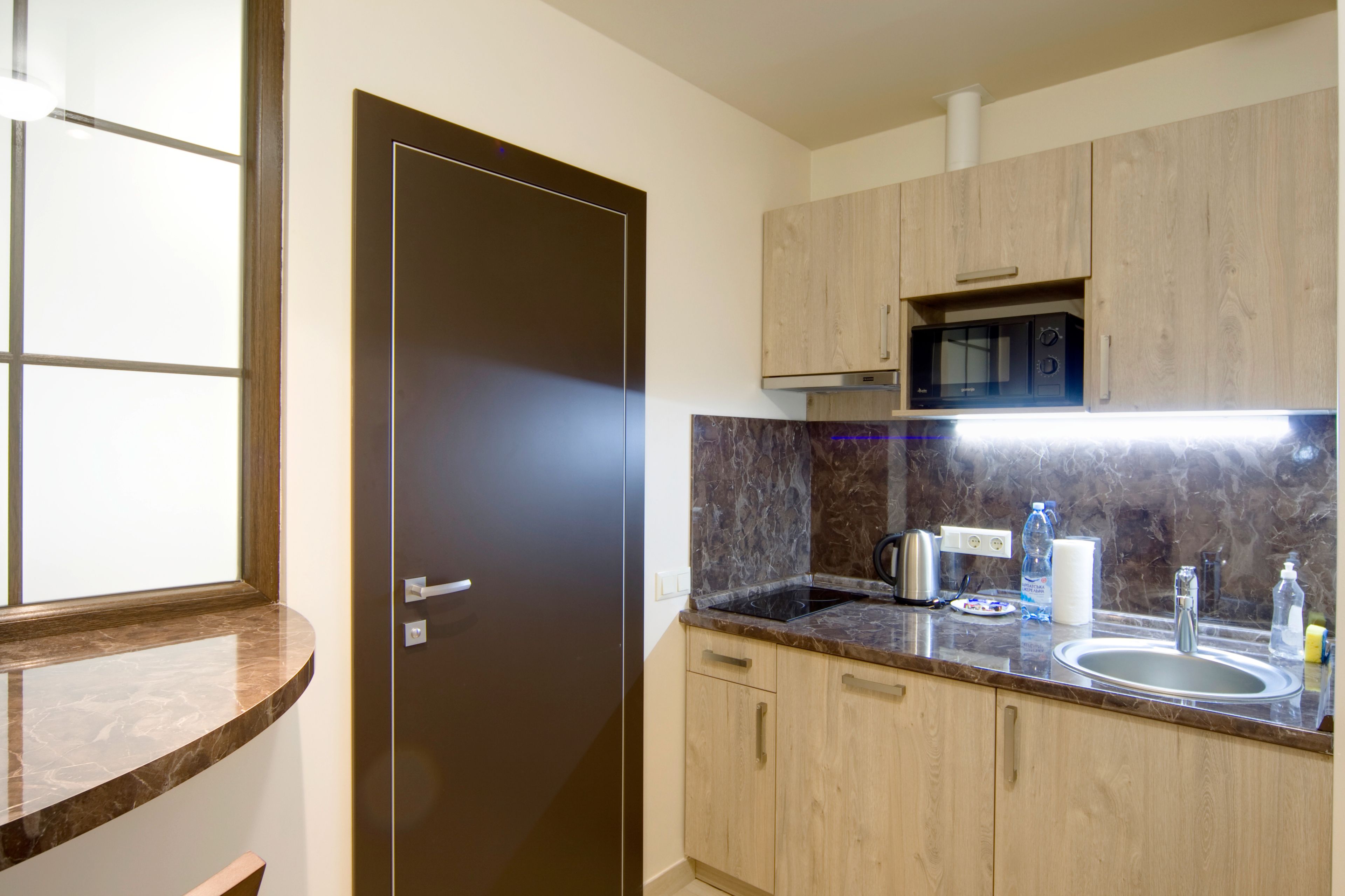 A modern kitchen with a marble countertop, stainless steel appliances, and wooden cabinets.