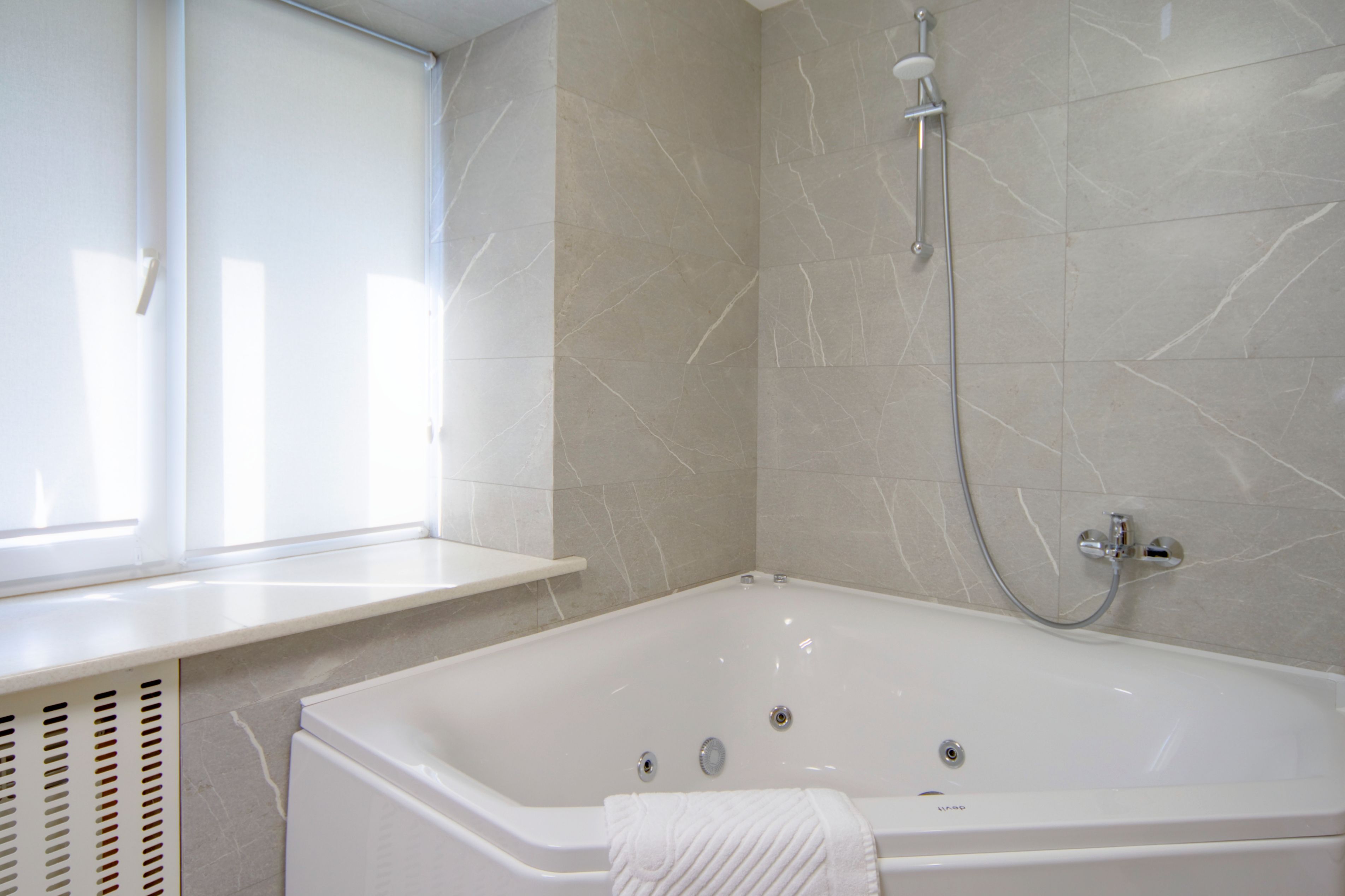 A bathroom with a white bathtub, a shower, and a window.