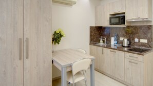A compact kitchen with a dining table, chairs, a microwave, and a sink.
