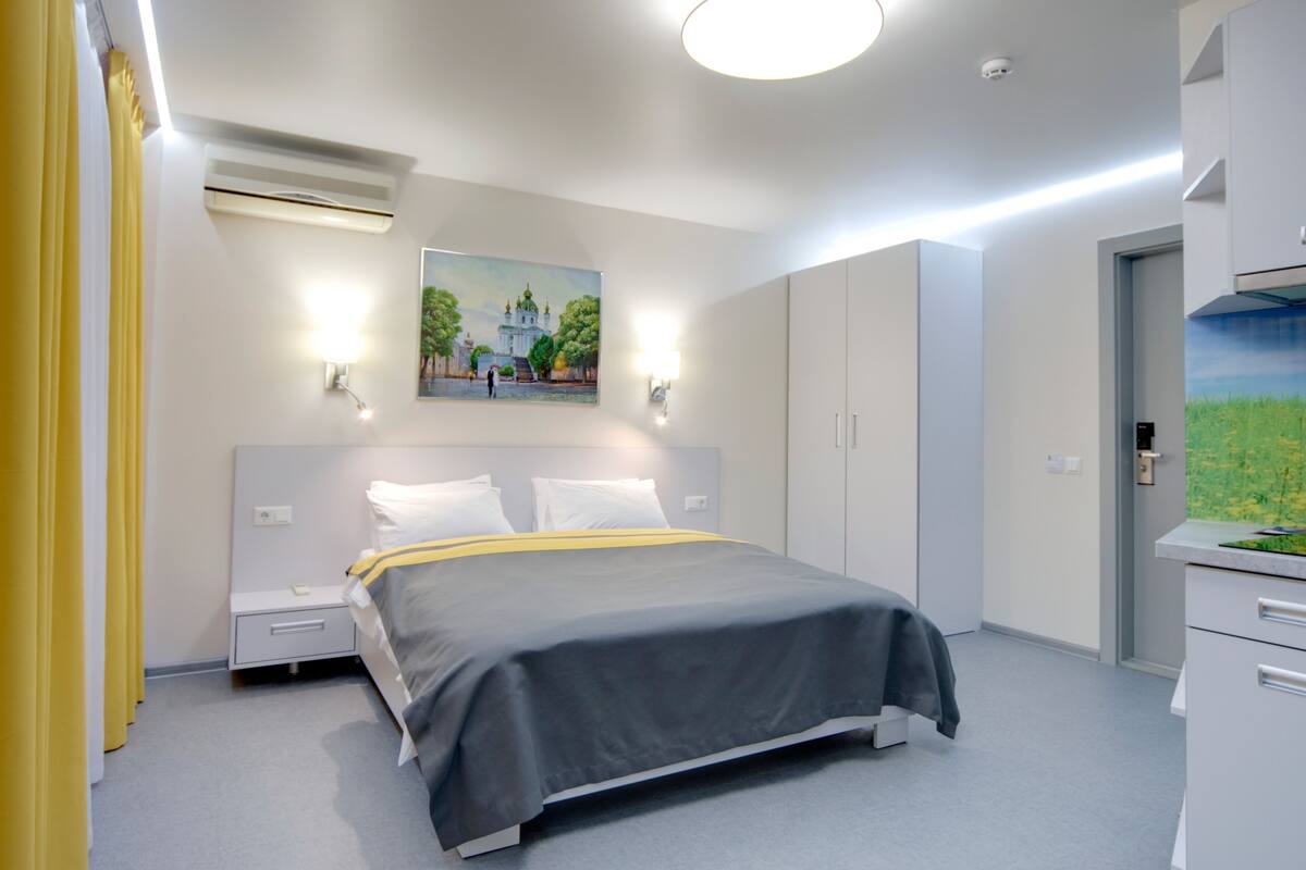 Ein modernes Schlafzimmer mit Bett, Nachttischen, einer Klimaanlage, einem Gemälde und einem Schreibtisch mit Schubladen.