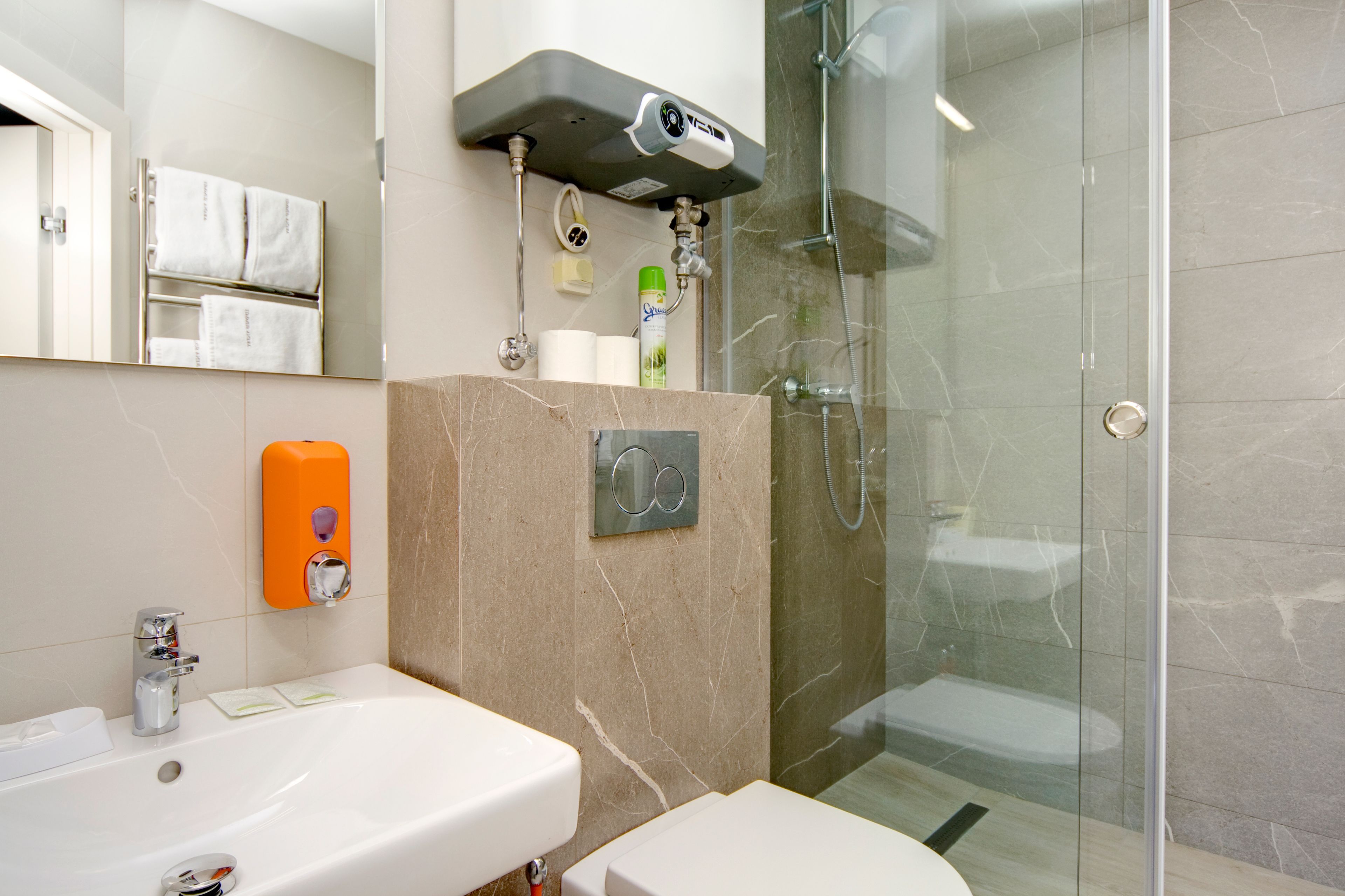 A modern bathroom with a glass-enclosed shower, a white sink, and a towel rack.