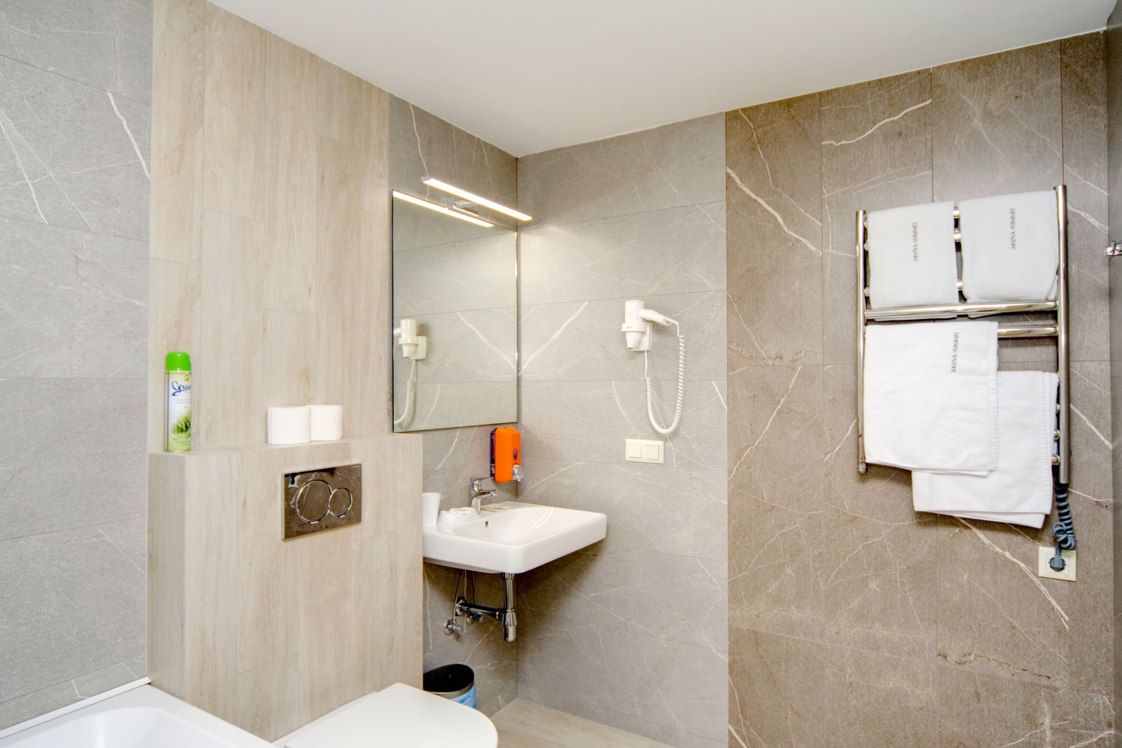 Un baño moderno con lavamanos, espejo, toallero y ducha.