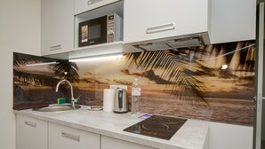 A modern kitchen with a microwave, kettle, and a decorative backsplash.