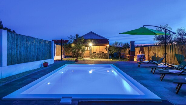 A swimming pool with a patio area, a barbecue grill, and a house in the background. - Gorgeous home in Bilice (Bilice)