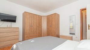 A bedroom with a bed, a wooden wardrobe, a television, and a window. - Gorgeous home in Bilice (Bilice)