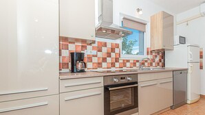 A modern kitchen with a built-in oven, a coffee maker, and a refrigerator. - Gorgeous home in Bilice (Bilice)