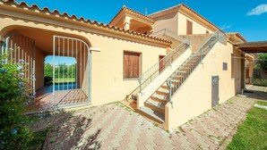 A two-story house with a tiled roof, a staircase, and a gated entrance. - 2 bedroom amazing apartment in San Teodoro OT (San Teodoro OT)