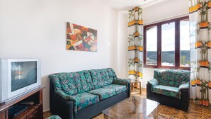 A living room with a sofa, a chair, a television, and a painting on the wall. - Stunning apartment in Porto Palma (Porto Palma)