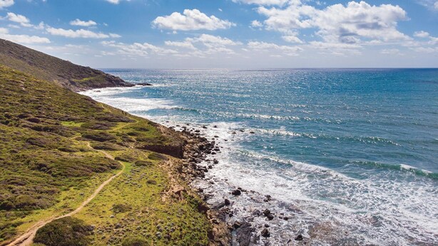 A coastal landscape with a rocky shoreline, a clear sky, and a path leading to the beach. - Stunning apartment in Porto Palma (Porto Palma)