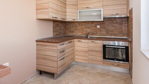 Eine kleine Küche mit Holzschränken, einem eingebauten Backofen und einer Edelstahl-Spüle.