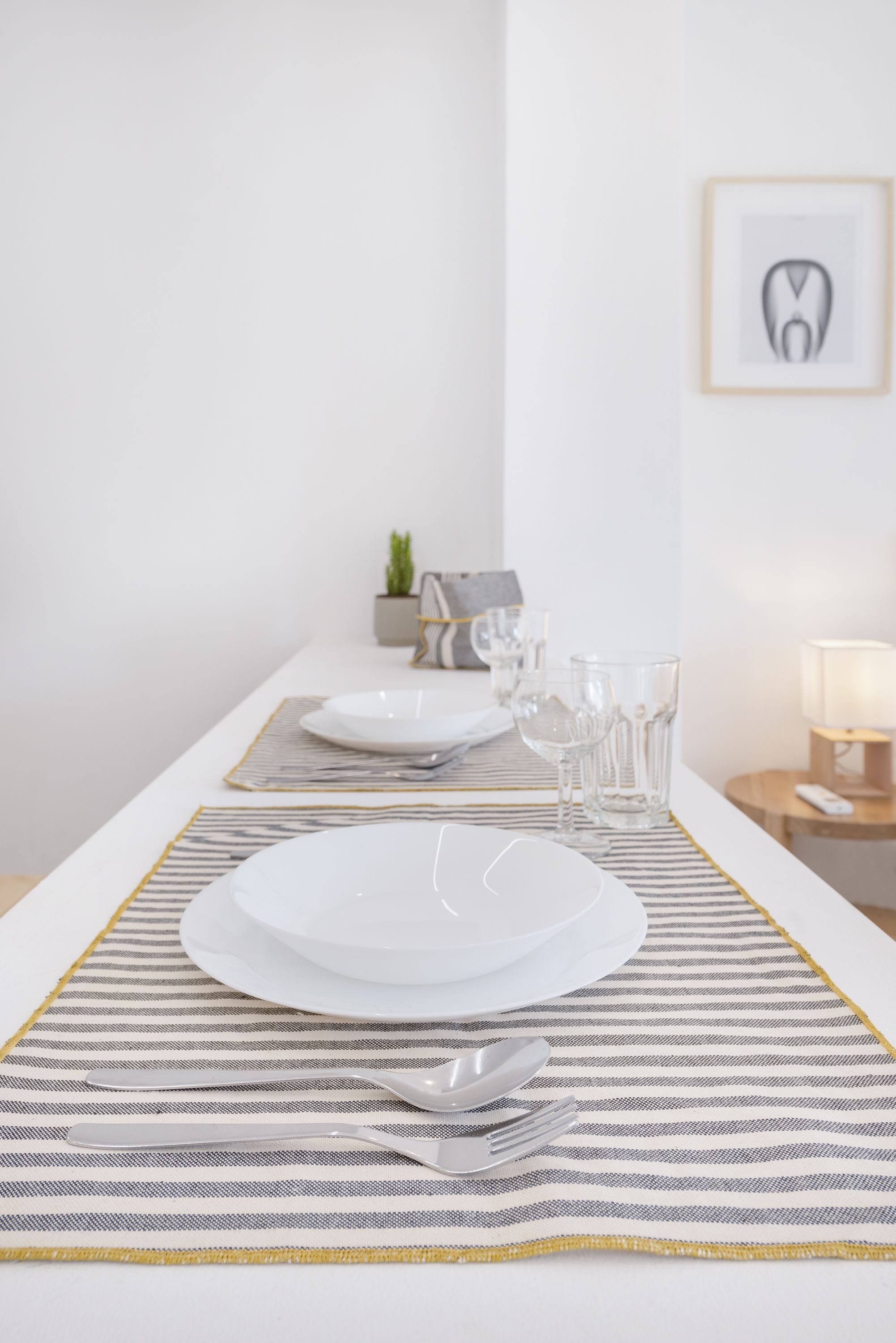 Een keurig gedekte eettafel met borden, bestek en glazen op een geruit placemat.