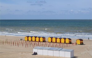 Ein Strand mit gelben Strandkörben und einem weißen Gebäude.