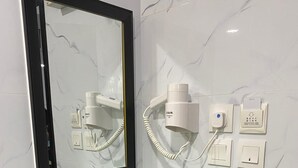 Un baño con espejo, secador de pelo y pulsador de luz.