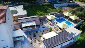 Vista aérea de una zona residencial con piscina, mobiliario exterior y un patio cubierto.