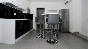 Una cocina moderna con una isla central, taburetes de bar, electrodomésticos de acero inoxidable y armarios blancos.