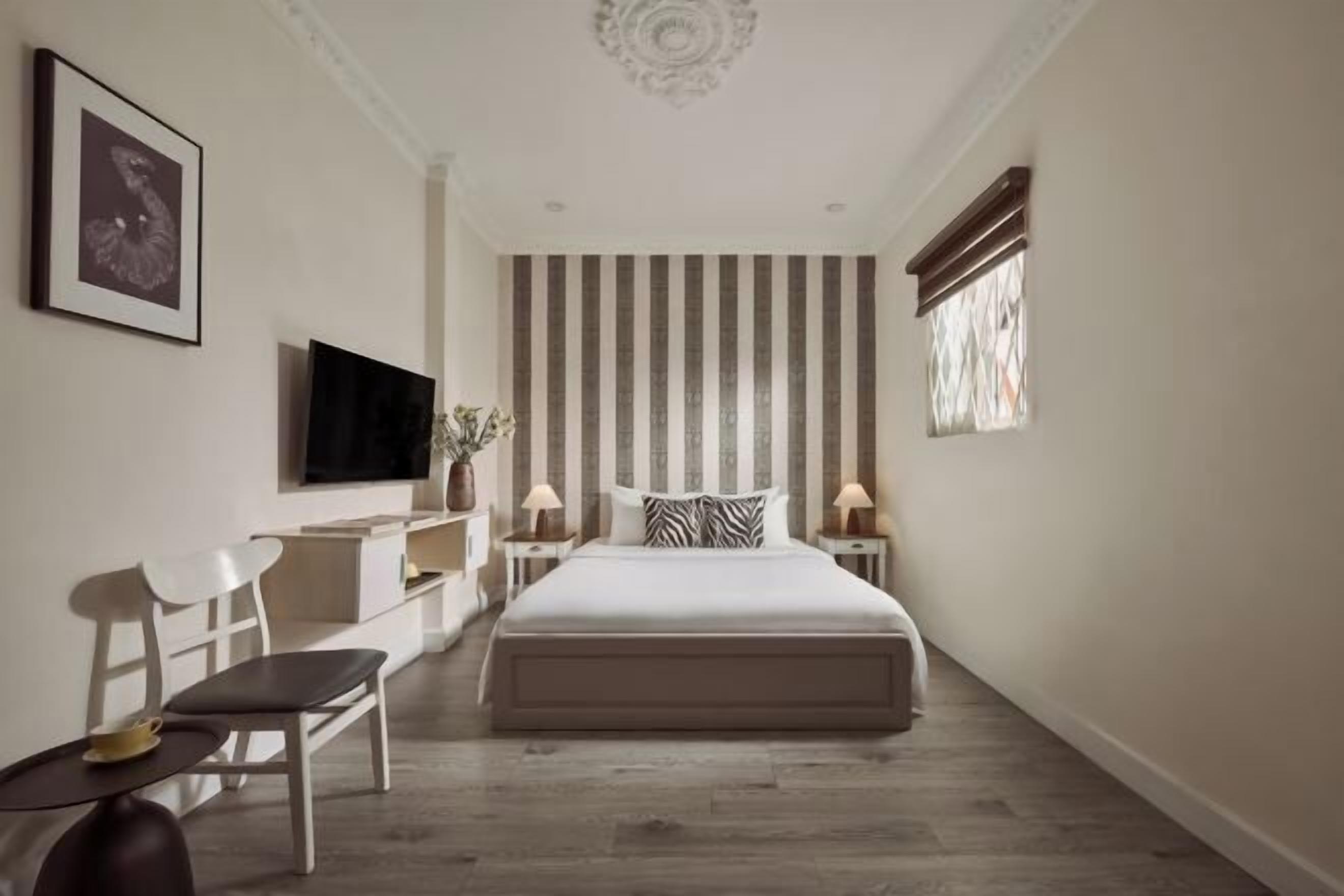 Ein Hotelzimmer mit Bett, Schreibtisch, Stuhl, Fernseher und Fenster.