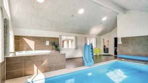 Ein Swimmingpool mit Rutsche, eine Whirlwanne und eine Sitzgelegenheit mit Stühlen.