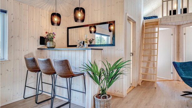 Ein Zimmer mit Holzwandverkleidung, einer Bar, zwei Barhocker, einem großen Spiegel und einer Zimmerpflanze.