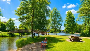 Ein Park mit einer Holzbrücke, einem Picknicktisch und einem Spielplatz.
