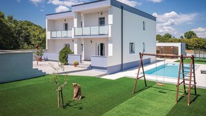 Ein modernes, zweistöckiges Haus mit Swimmingpool, Holzschaukel und einem kleinen Garten.