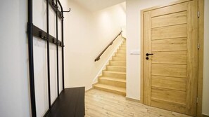 A staircase with a wooden handrail, a wooden door, and a wall-mounted coat rack. - Apartamenty EverySky Luxor Karkonoska (Karpacz)